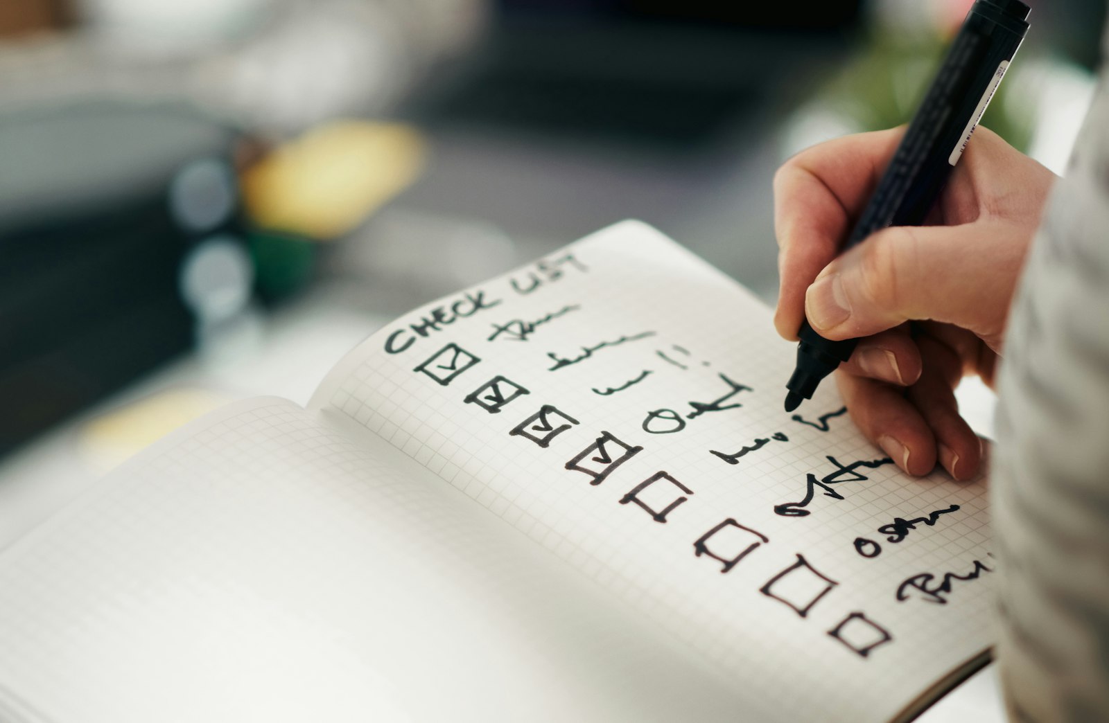 Hand checking off items on a checklist in a notebook