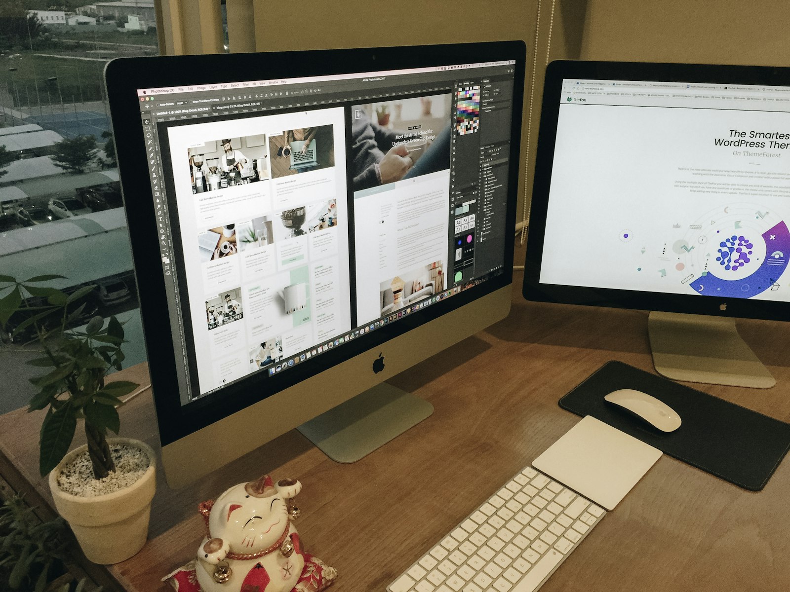 Web designer's desk with website layouts on two monitors
