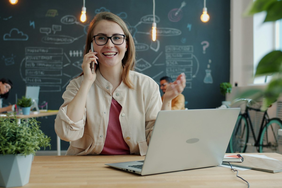 Office manager smiling on a business phone call in a modern office