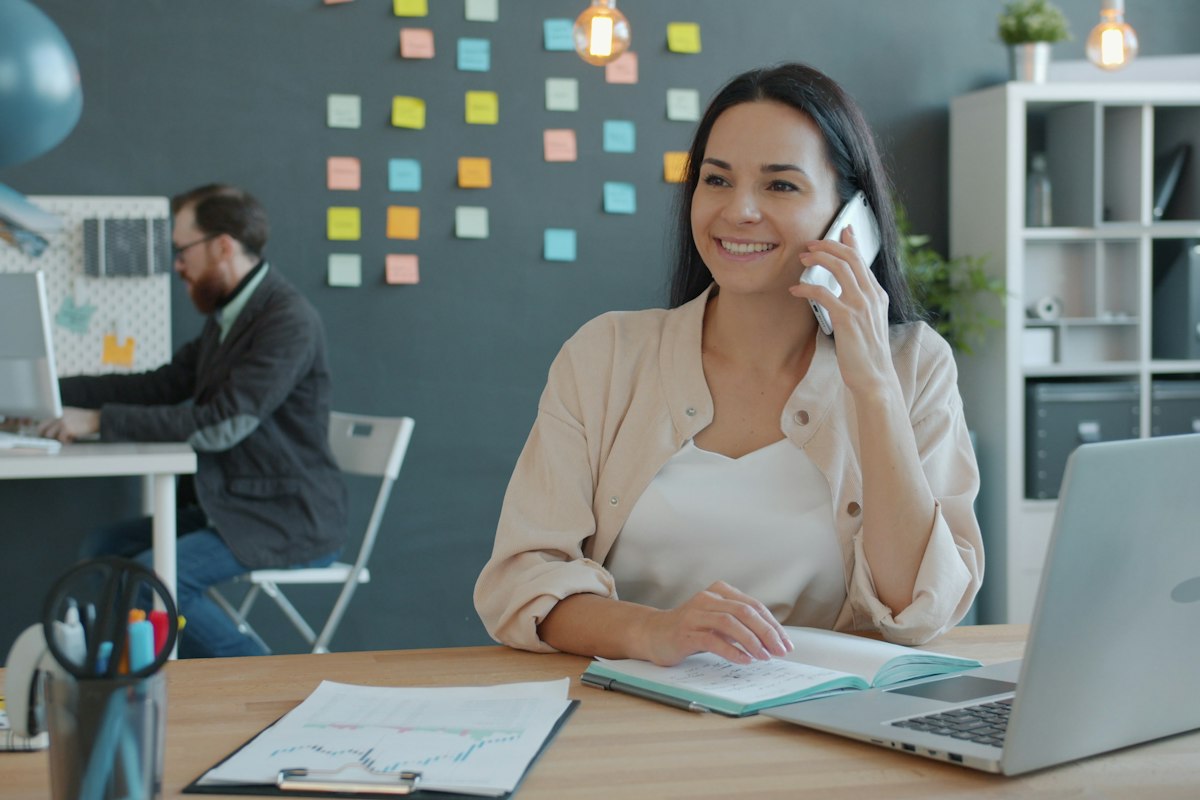 Smiling receptionist answering a client call at a bright office desk